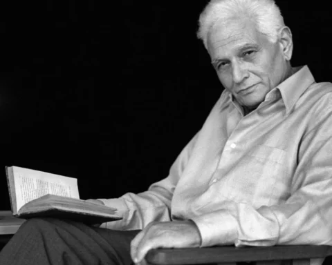 Retrato en blanco y negro de Jacques Derrida sentado en una silla, con un libro abierto en la mano y una vela encendida sobre una mesa a su lado, en un ambiente íntimo y reflexivo.