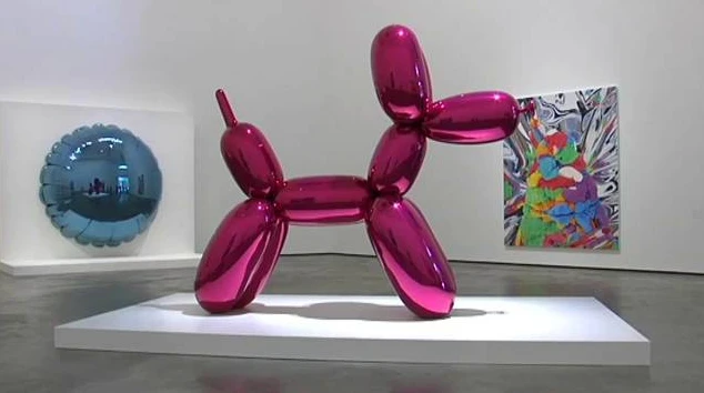 Escultura metálica rosa con forma de perro globo expuesta en una sala de museo de arte contemporáneo.