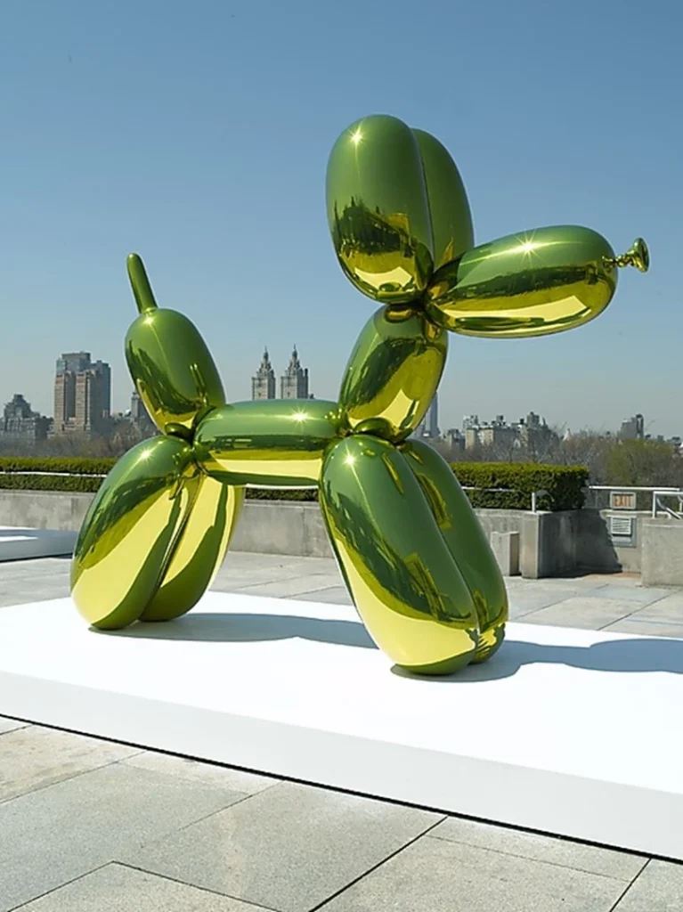 Escultura brillante verde con forma de perro globo instalada en una terraza urbana con rascacielos al fondo.