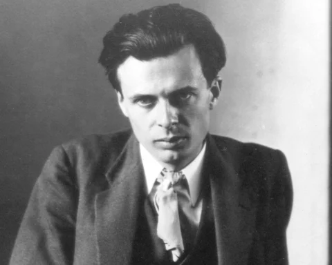Retrato en blanco y negro de un joven hombre con traje y mirada seria posando frente a un fondo neutro.