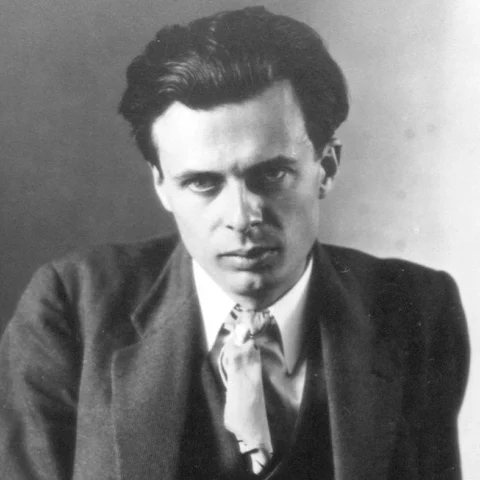 Retrato en blanco y negro de un joven hombre con traje y mirada seria posando frente a un fondo neutro.
