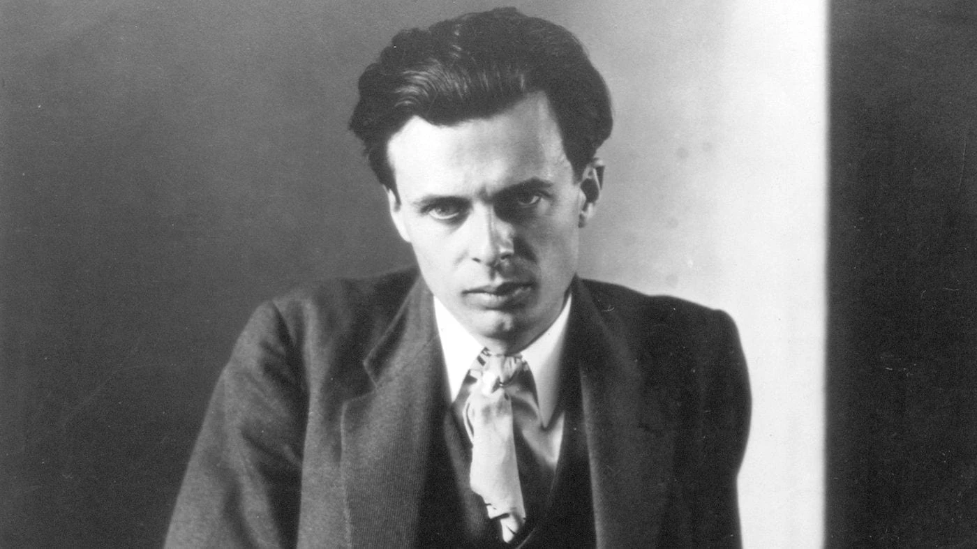 Retrato en blanco y negro de un joven hombre con traje y mirada seria posando frente a un fondo neutro.